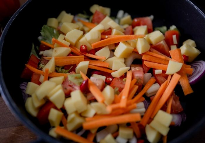 sliced carrots and green vegetable in black ceramic bowl